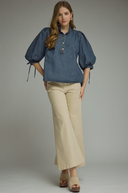 A feminine lightweight denim top featuring romantic ¾ puff sleeves, a classic button-front closure, and adjustable self-tie cuffs for a polished everyday look.