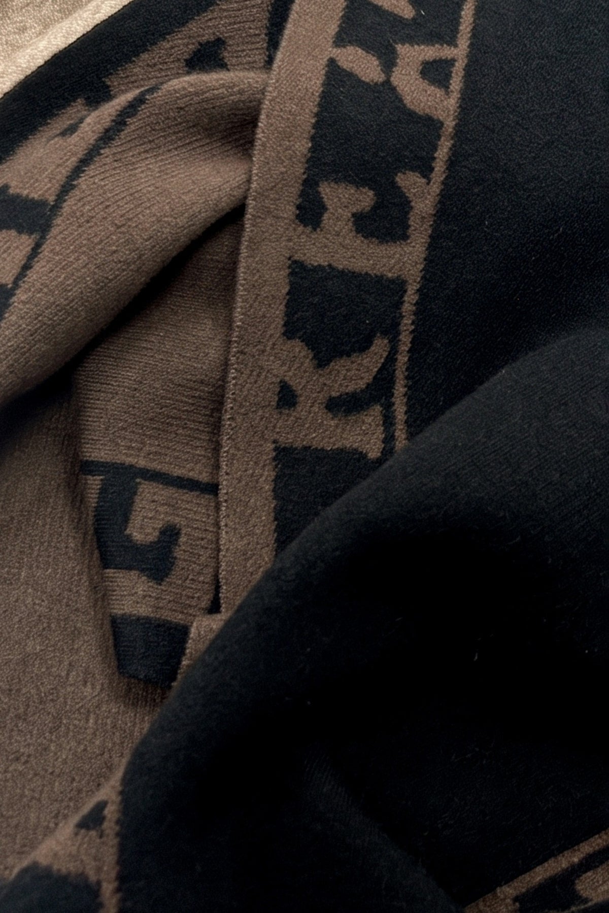 A cozy knit triangle scarf featuring reversible color blocking and stylish lettering details for a versatile cold-weather accessory.