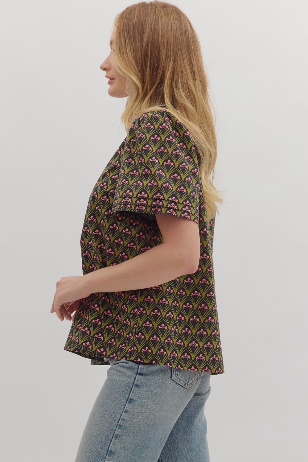 The Evangeline top combines bold geometric print with a chic ruffled mock neck and adjustable tie-front detail.