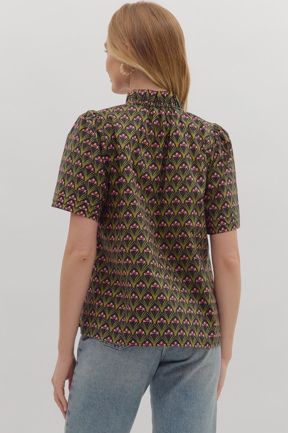 The Evangeline top combines bold geometric print with a chic ruffled mock neck and adjustable tie-front detail.