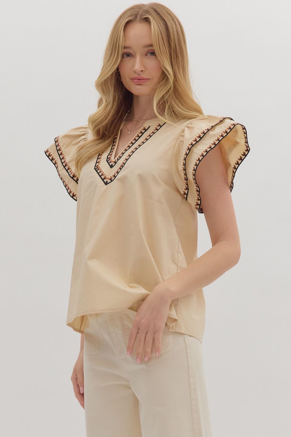 Feminine and breezy, the Odette top features layered flutter sleeves, a V-neck, and contrast embroidered trim for a polished finish.
