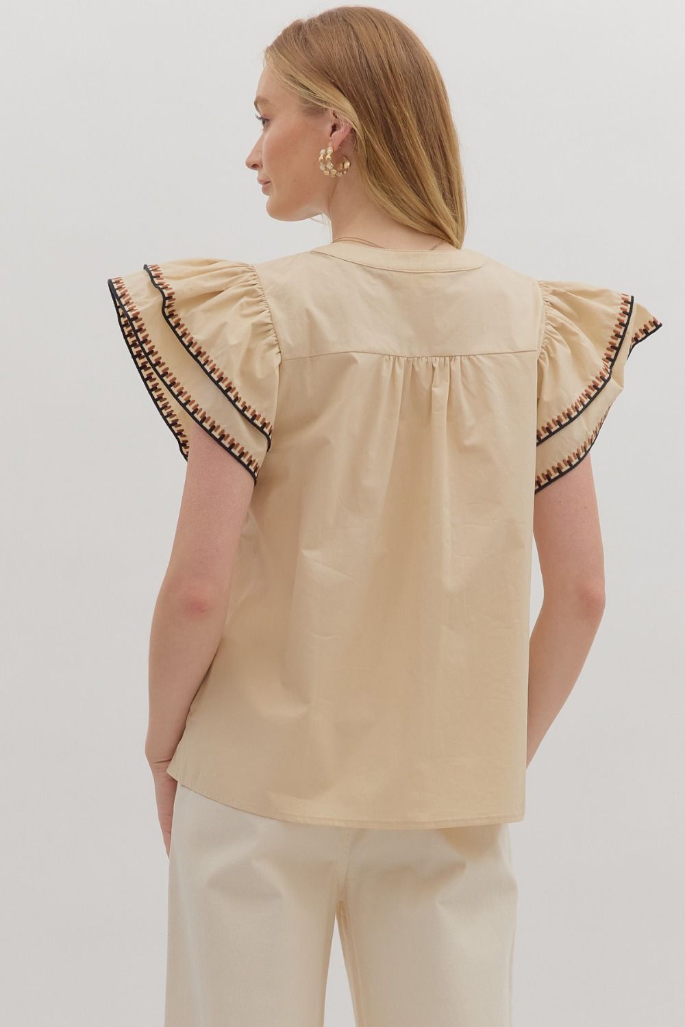 Feminine and breezy, the Odette top features layered flutter sleeves, a V-neck, and contrast embroidered trim for a polished finish.