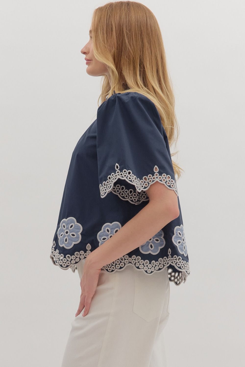 Romantic and airy, the Felicity top features floral embroidery, flutter sleeves, and a scalloped hem with a ruffled high neck.