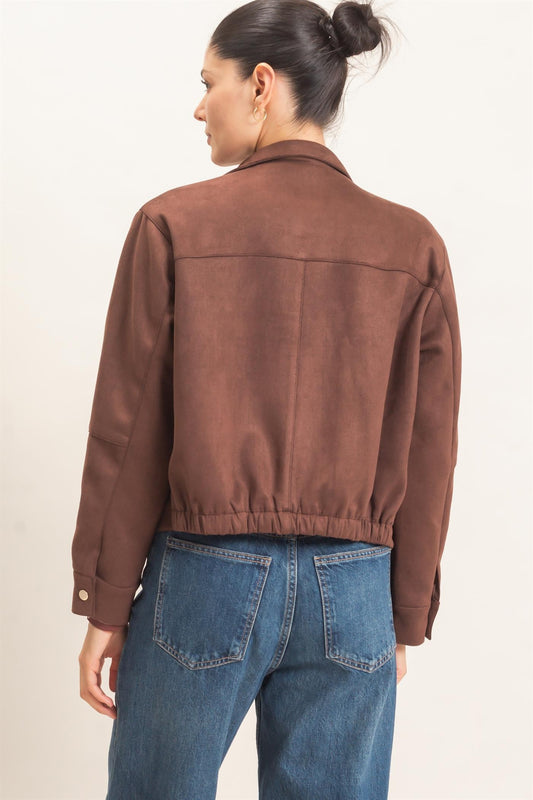 A polished faux suede jacket featuring a structured silhouette, high collar, metal snap closures, subtle stitching, and convenient side pockets.