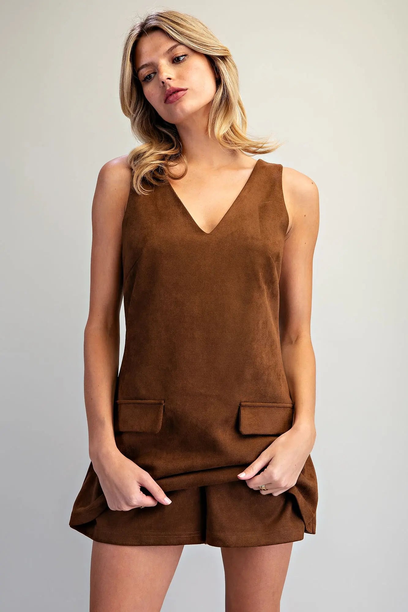 A vintage-inspired faux suede skort romper featuring a flattering V-neckline, A-line silhouette, and hidden shorts for effortless style and comfort.