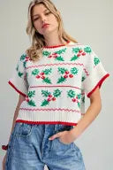 A festive short-sleeve knit top featuring a charming holly red-and-green floral pattern, relaxed fit, and playful contrast trim for standout seasonal style.