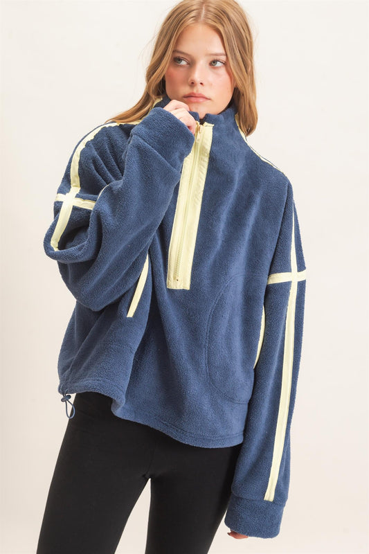 A cozy fleece half zip pullover featuring a high funnel neck, sporty contrast trim, oversized curved pockets, and an adjustable drawstring hem.