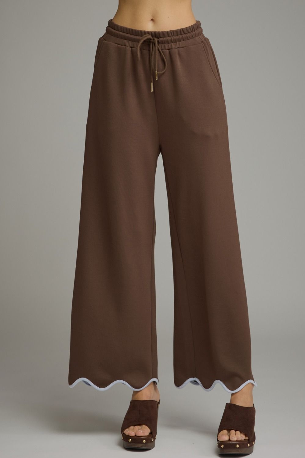 A polished two-piece knit set featuring a feminine scallop-trim top and coordinating drawstring pants for an effortlessly chic look from lounging to lunch.