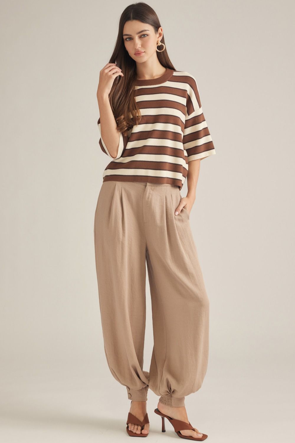 Polished woven pants featuring elegant front pleats, a comfortable elastic-back waist, and buttoned cuffs for an effortlessly tailored look.