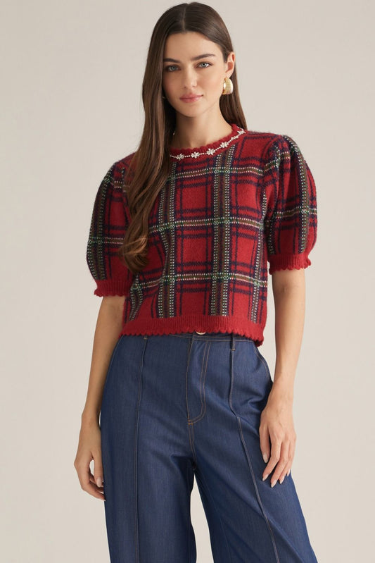 A charming plaid knit top featuring feminine puff sleeves, delicate embellished trim, and scalloped edges for a polished, vintage-inspired look.