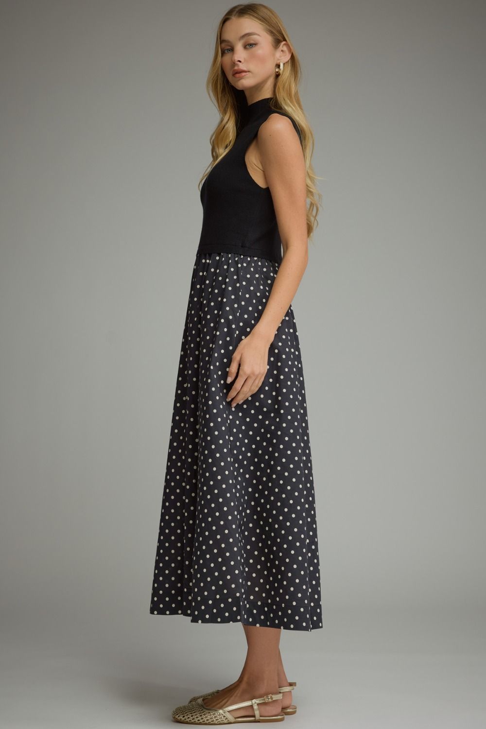 A sophisticated polka dot midi dress featuring a sleek solid knit bodice, mock neckline, and feminine flowing silhouette.