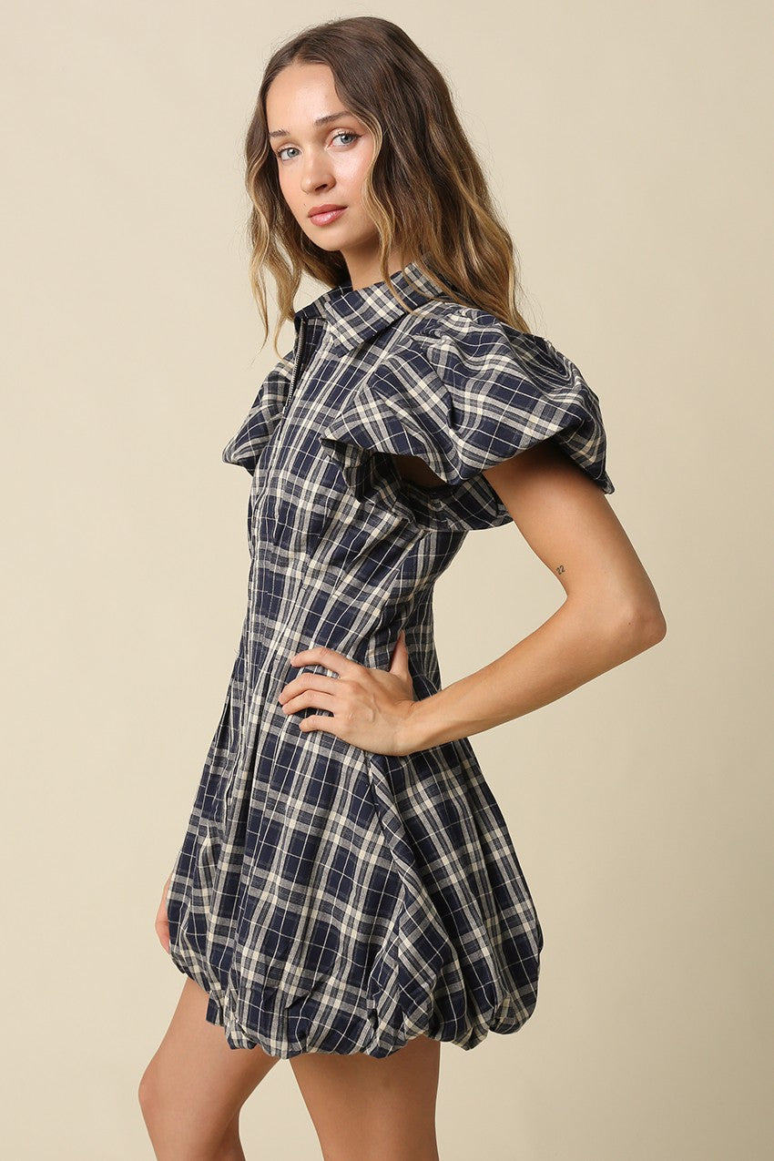 A fashion-forward plaid mini dress featuring a collared zip-front neckline, puff sleeves, and a voluminous bubble hem for standout seasonal style.