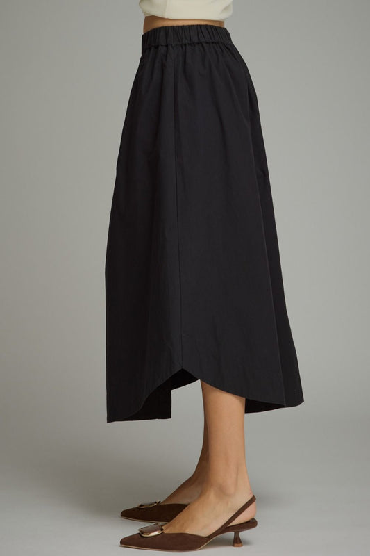A timeless midi skirt featuring a button-front design, comfortable elastic waistband, and functional side pockets for effortless everyday elegance.