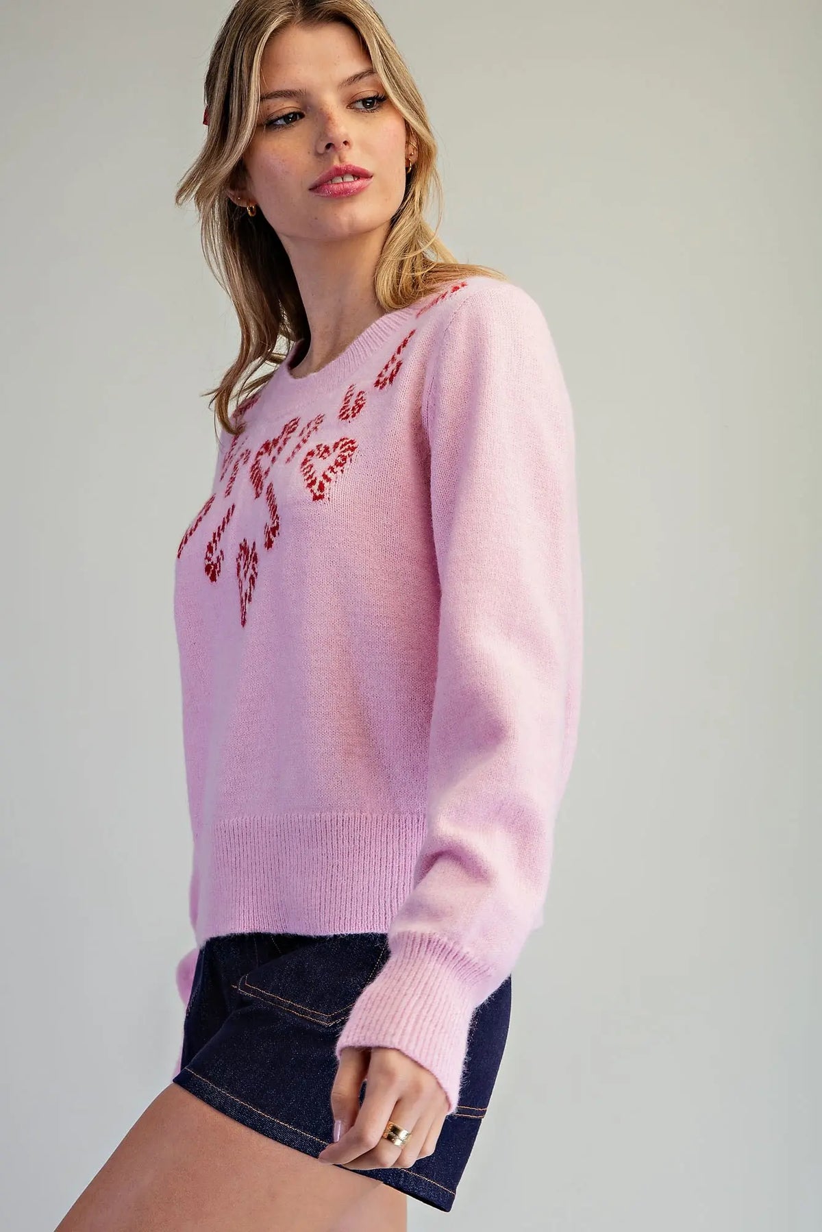 A cozy festive knit sweater featuring candy cane heart motifs, a classic crew neckline, and wide ribbed trims for a charming holiday look.