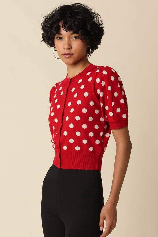 A feminine cropped polka dot cardigan featuring short puff sleeves, a scalloped hem, and a flattering fitted silhouette in a soft stretch wool blend.
