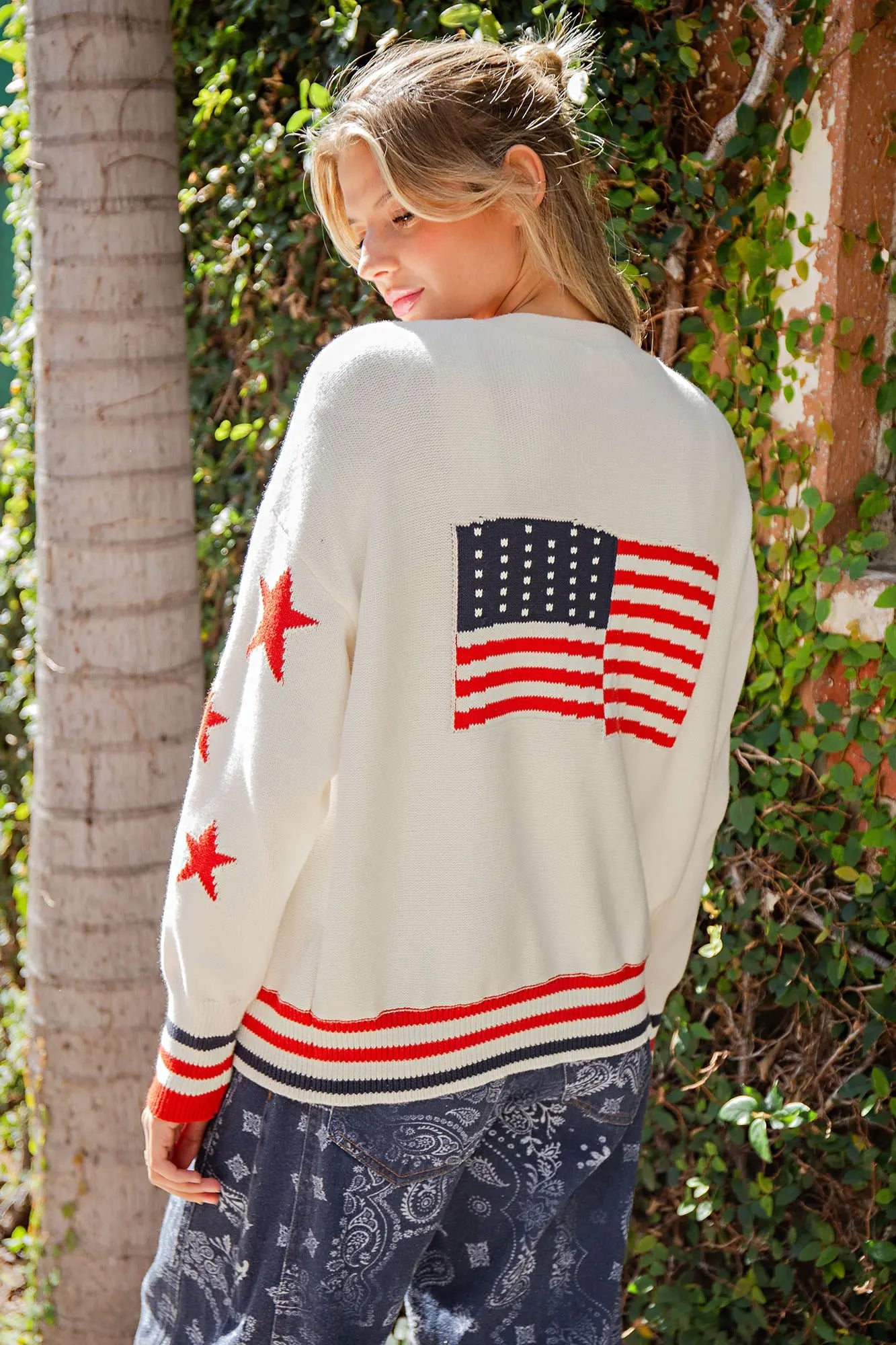 Oversized cotton cardigan featuring star-pattern sleeves, button-front closure, front pockets, and a bold American flag graphic on the back.