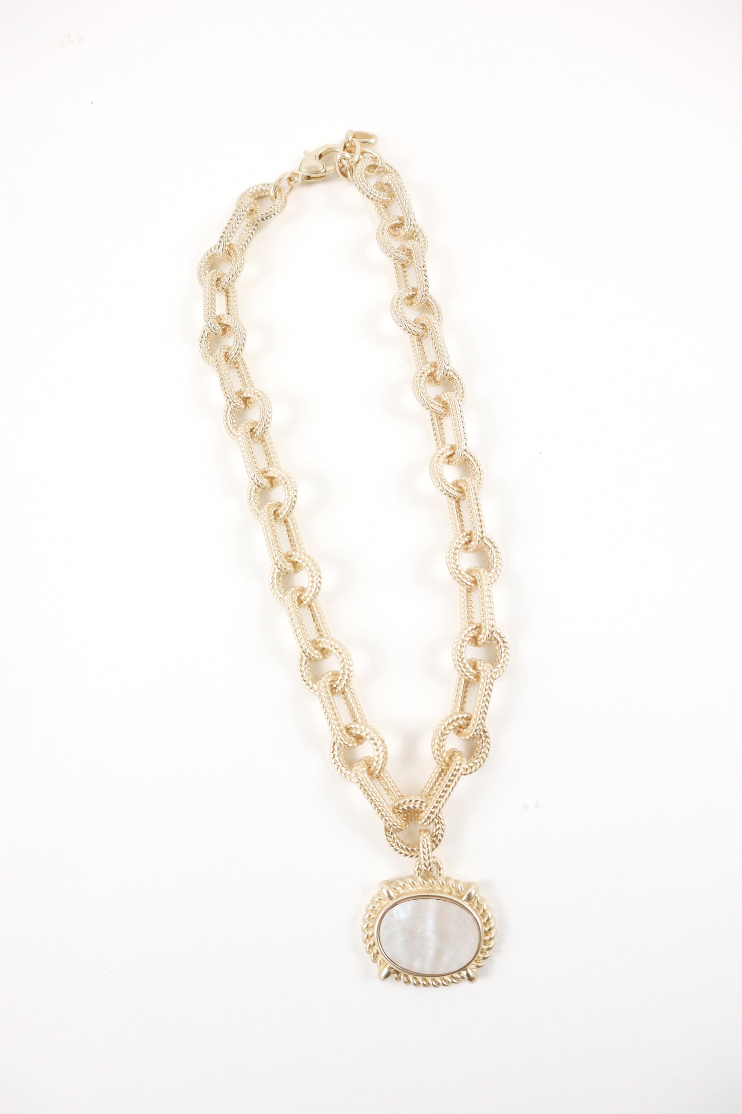 Gold textured link chain necklace with oval mother-of-pearl pendant and rope detailing, women’s boutique coastal statement jewelry.