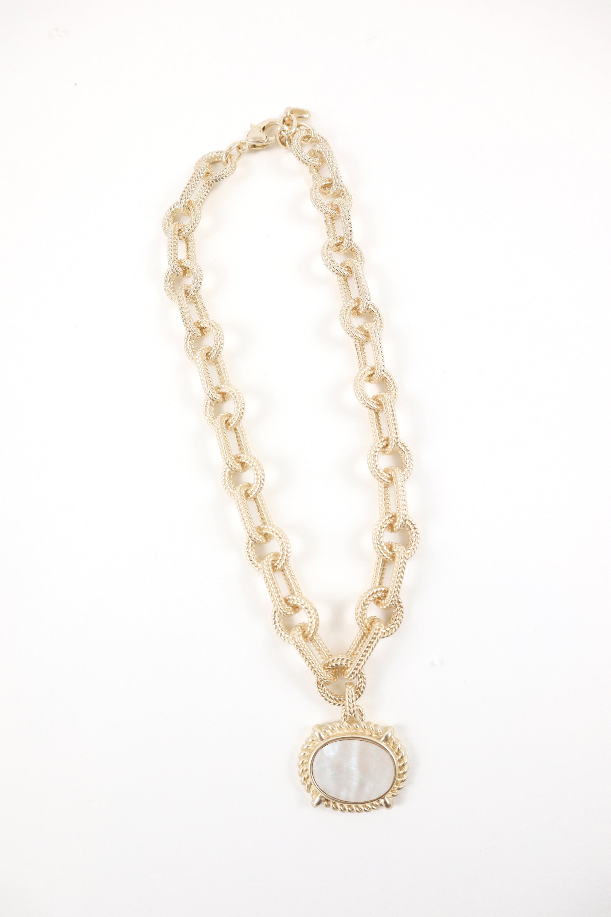 Gold textured link chain necklace with oval mother-of-pearl pendant and rope detailing, women’s boutique coastal statement jewelry.