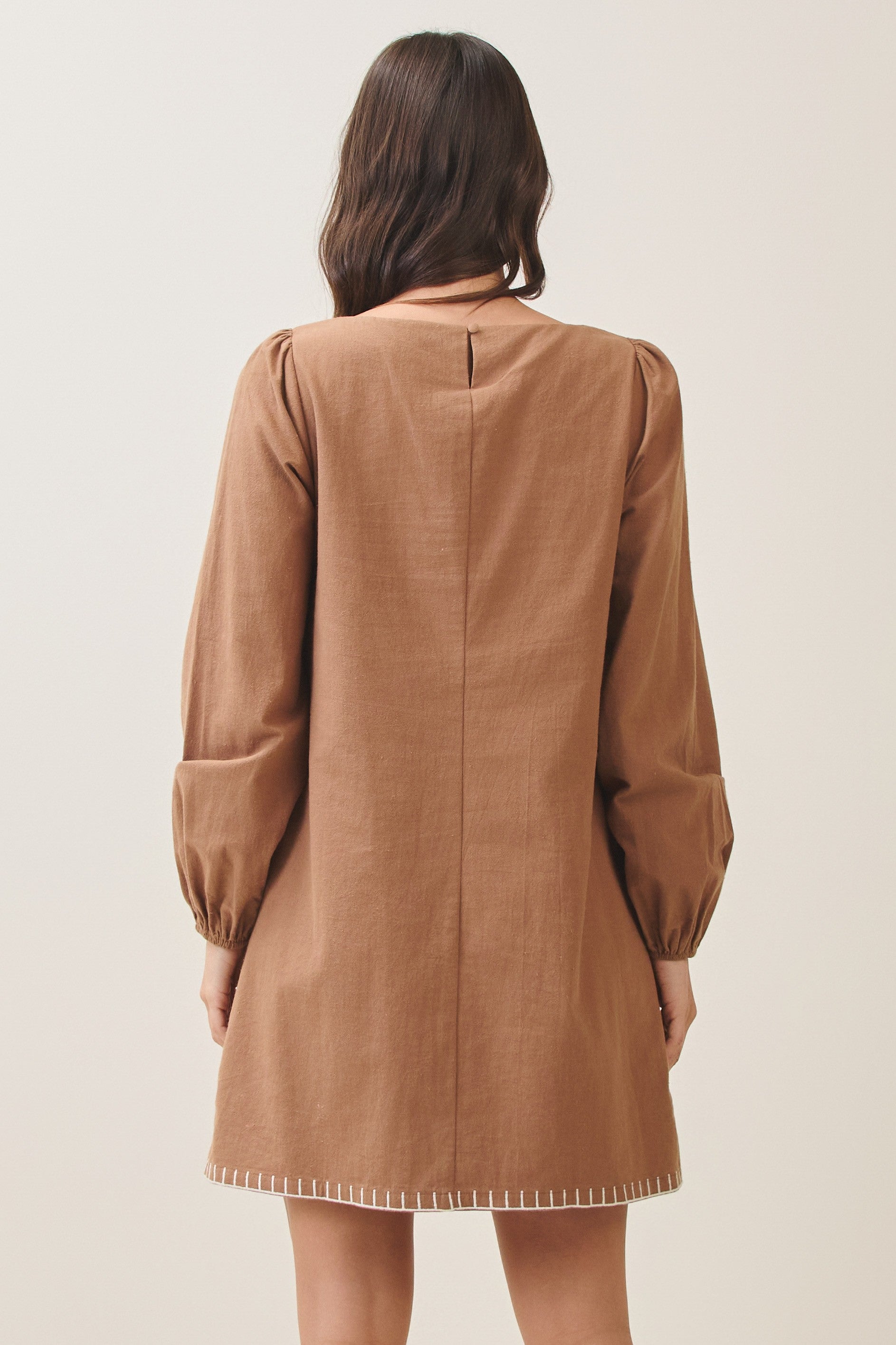 100% cotton embroidered mini dress featuring long volume sleeves, decorative whipstitch detailing, and a relaxed feminine silhouette.