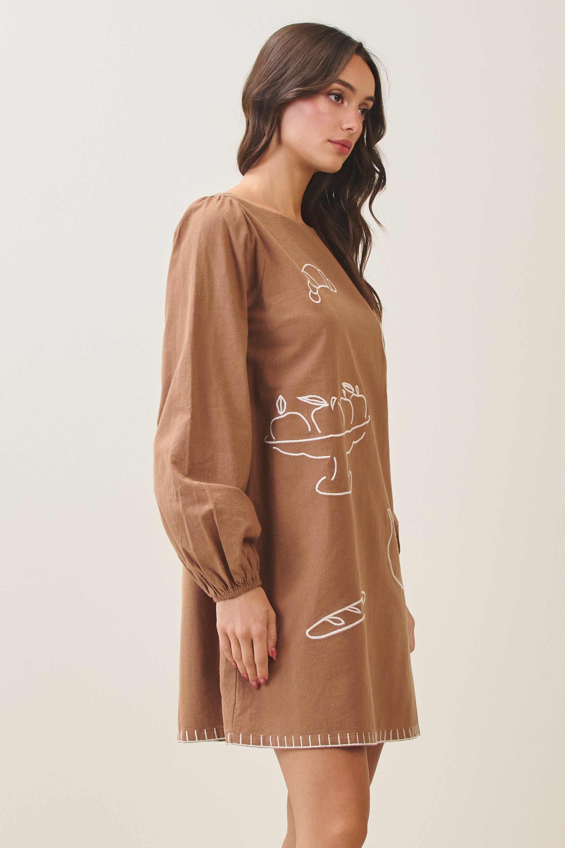100% cotton embroidered mini dress featuring long volume sleeves, decorative whipstitch detailing, and a relaxed feminine silhouette.