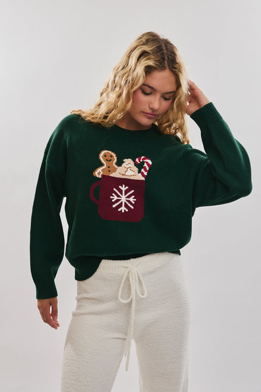 Spread cozy holiday cheer in this playful sweater featuring a festive cocoa mug motif.