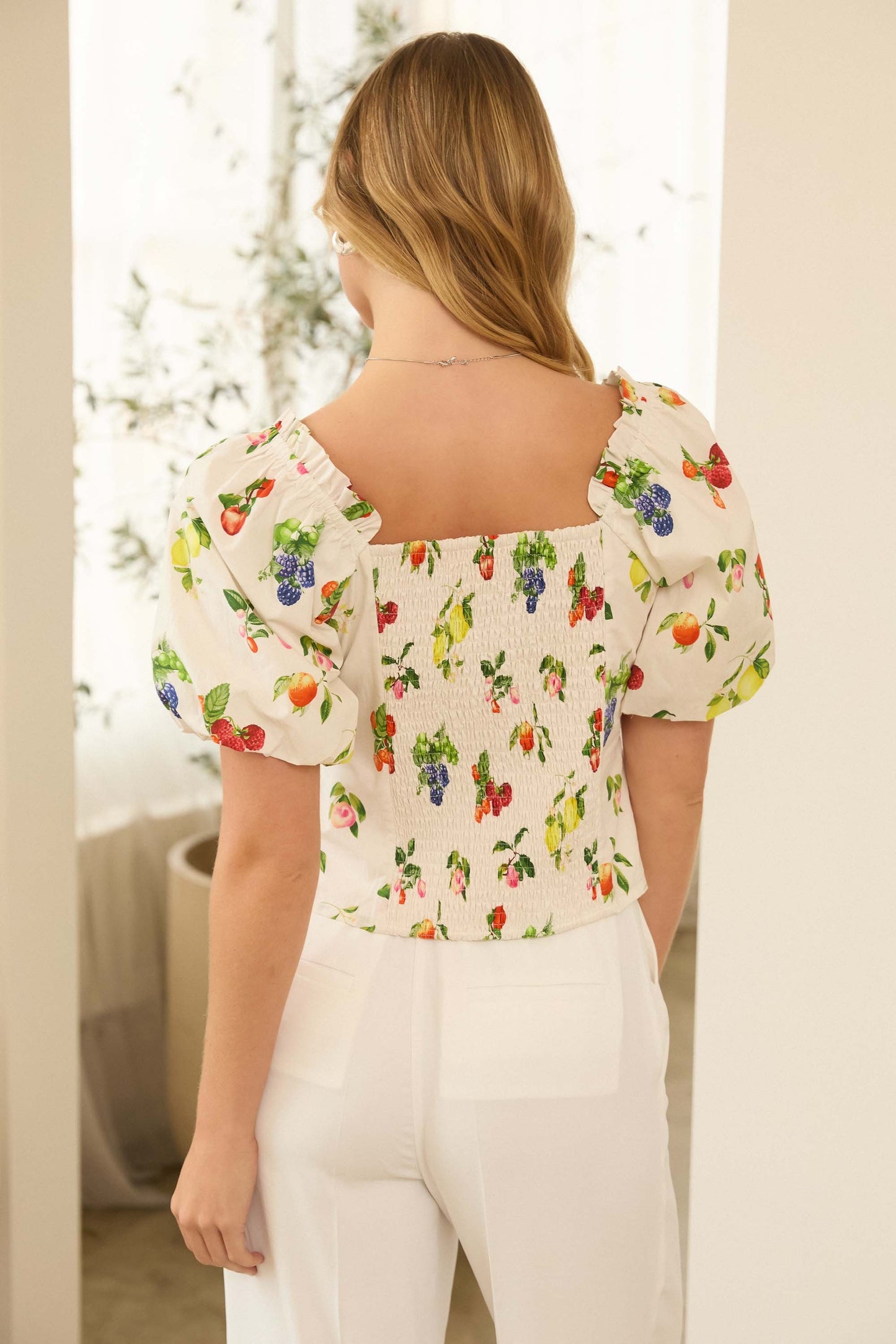 Fruit print bubble sleeve top featuring a lightweight fabric, vibrant allover fruit pattern, and voluminous short sleeves for a playful, summery look.