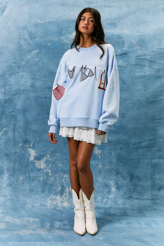 light blue cotton sweatshirt featuring playful summer bathing suit graphics