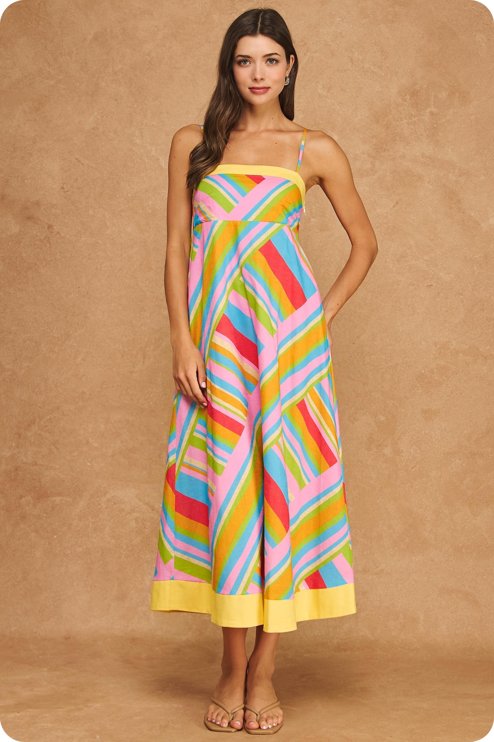 Colorful geometric stripe midi dress featuring a square neckline, adjustable spaghetti straps, empire waist silhouette, smocked back, hidden pockets, and contrast yellow trim.

