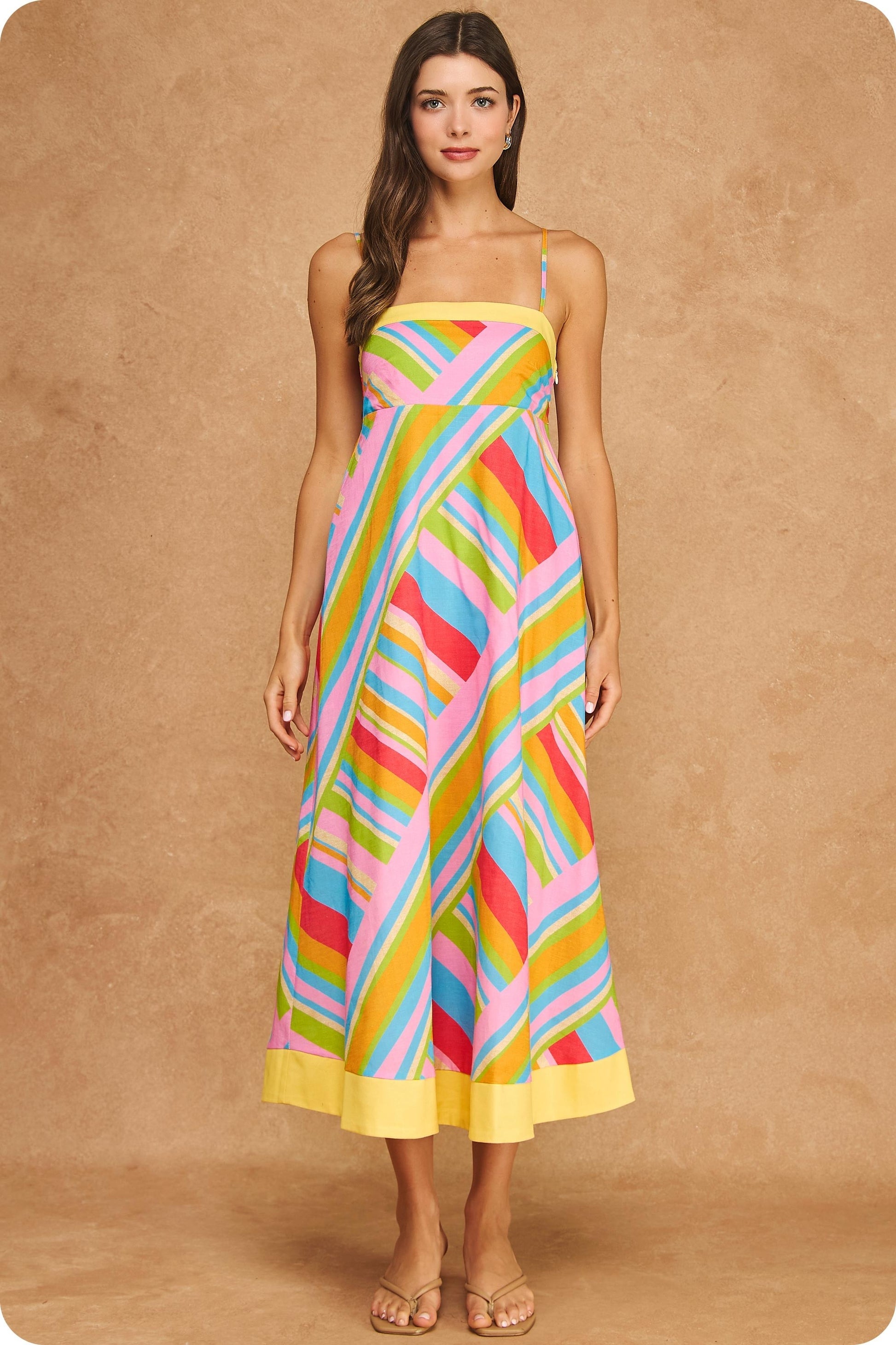 Colorful geometric stripe midi dress featuring a square neckline, adjustable spaghetti straps, empire waist silhouette, smocked back, hidden pockets, and contrast yellow trim.
