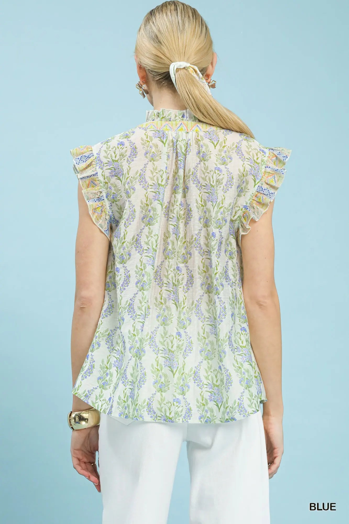 lightweight floral top featuring flutter cap sleeves, a ruffled split neckline, and contrast trim accents