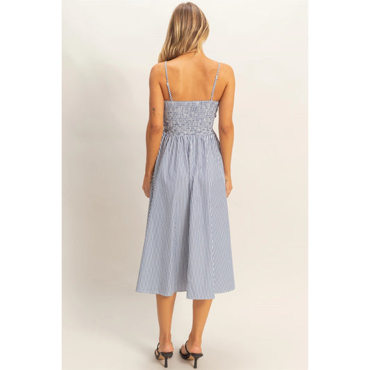Woman wearing a blue and white striped midi sundress with spaghetti straps and fit-and-flare silhouette, lightweight summer dress styled with black sandals.