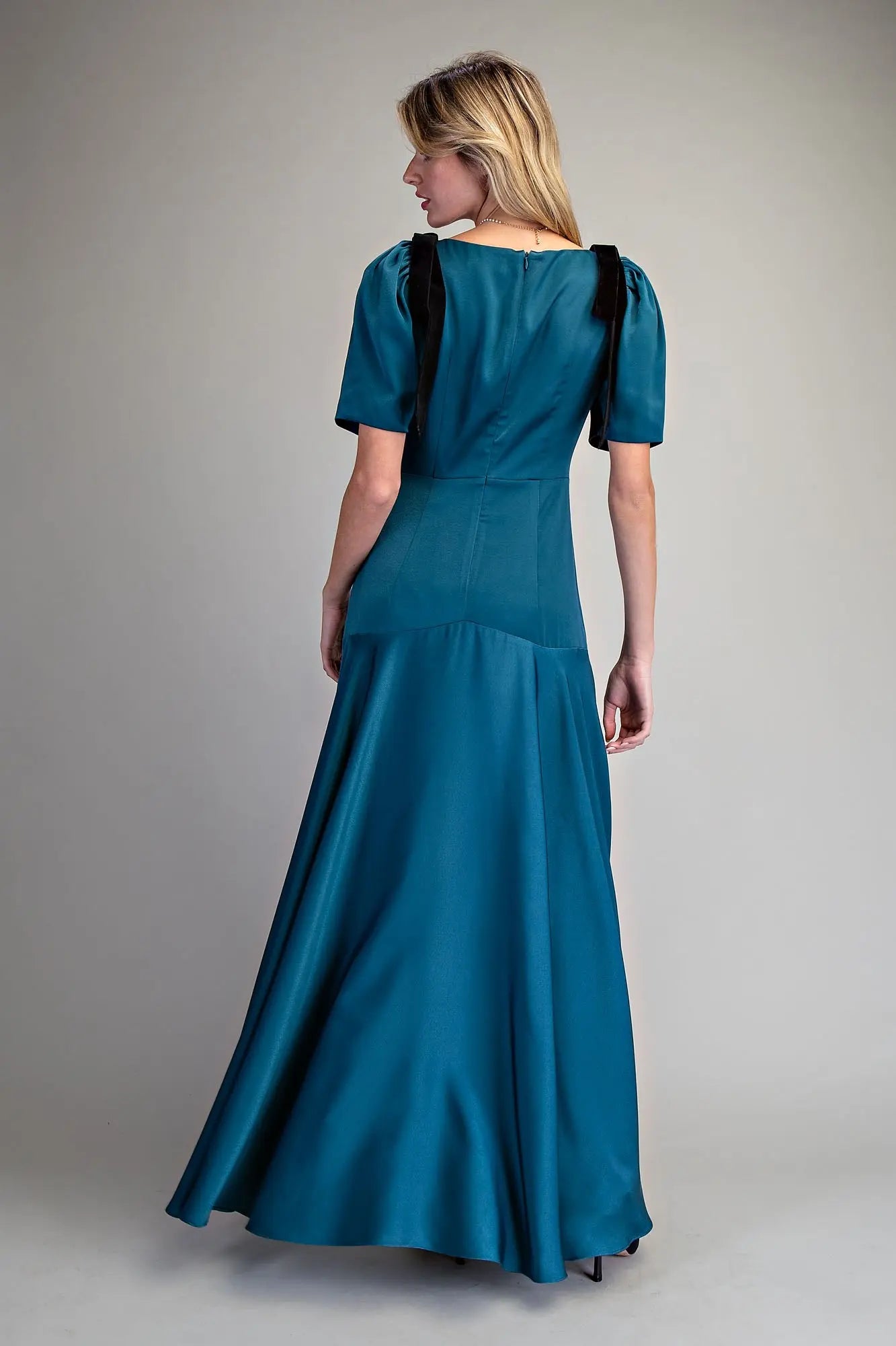 A romantic satin maxi dress with velvet bow tie sleeves, a plunging V-neckline, and a flowing A-line skirt.