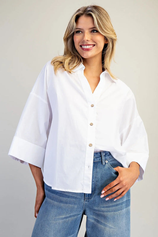 Woman wearing a white blouse and blue jeans against a plain background