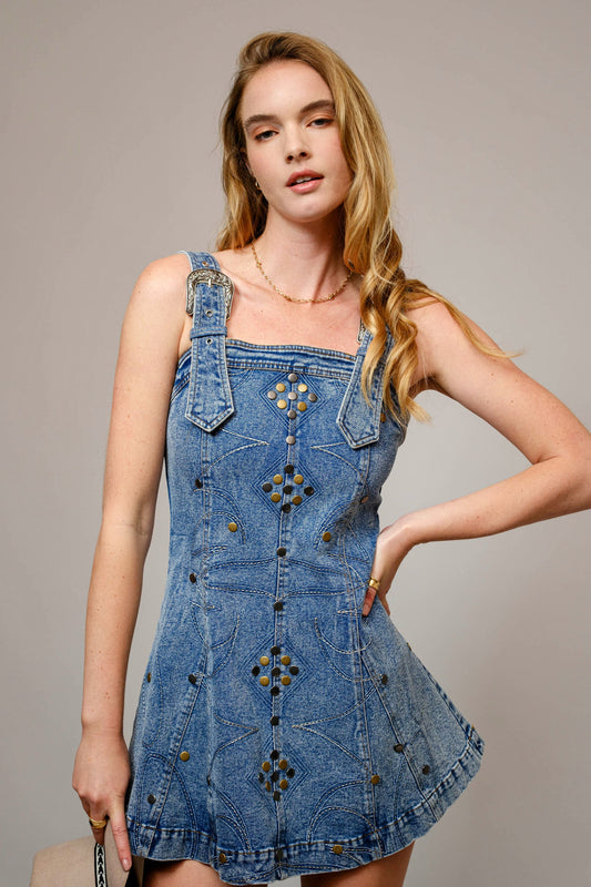 A curve-loving stretch denim dress with studded accents, western stitching, and bold buckle straps.

