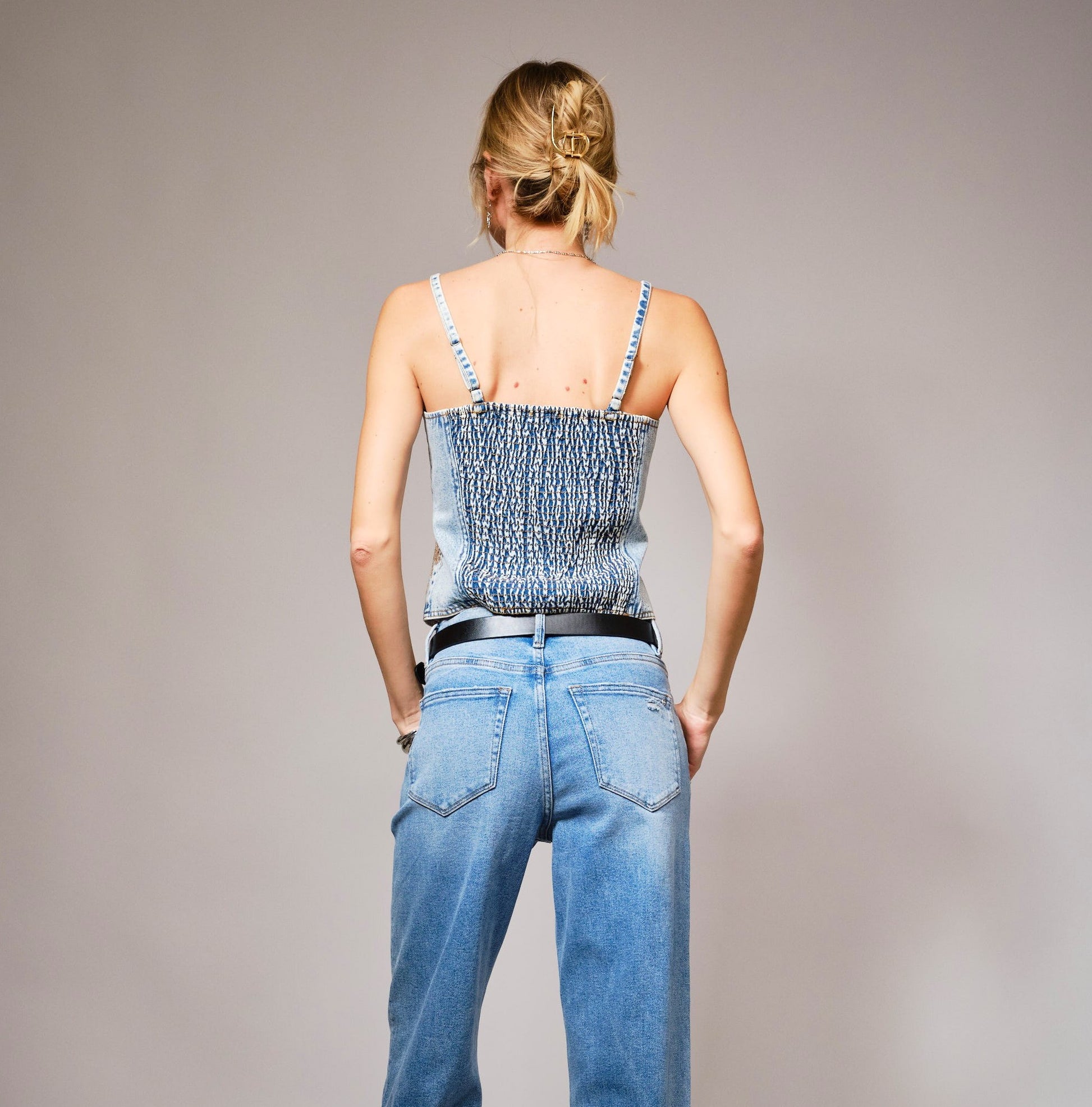 A denim corset top with sparkling sequin bow embroidery and a flattering structured fit.