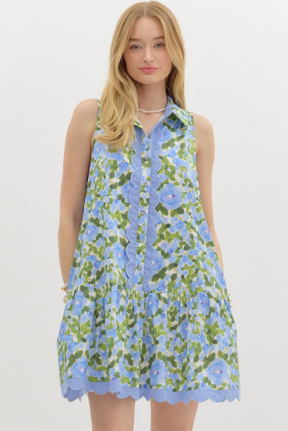 A floral sleeveless mini dress with a shirt collar, scalloped embroidery, and ruffle hem—playful, polished, and perfect for warm weather.