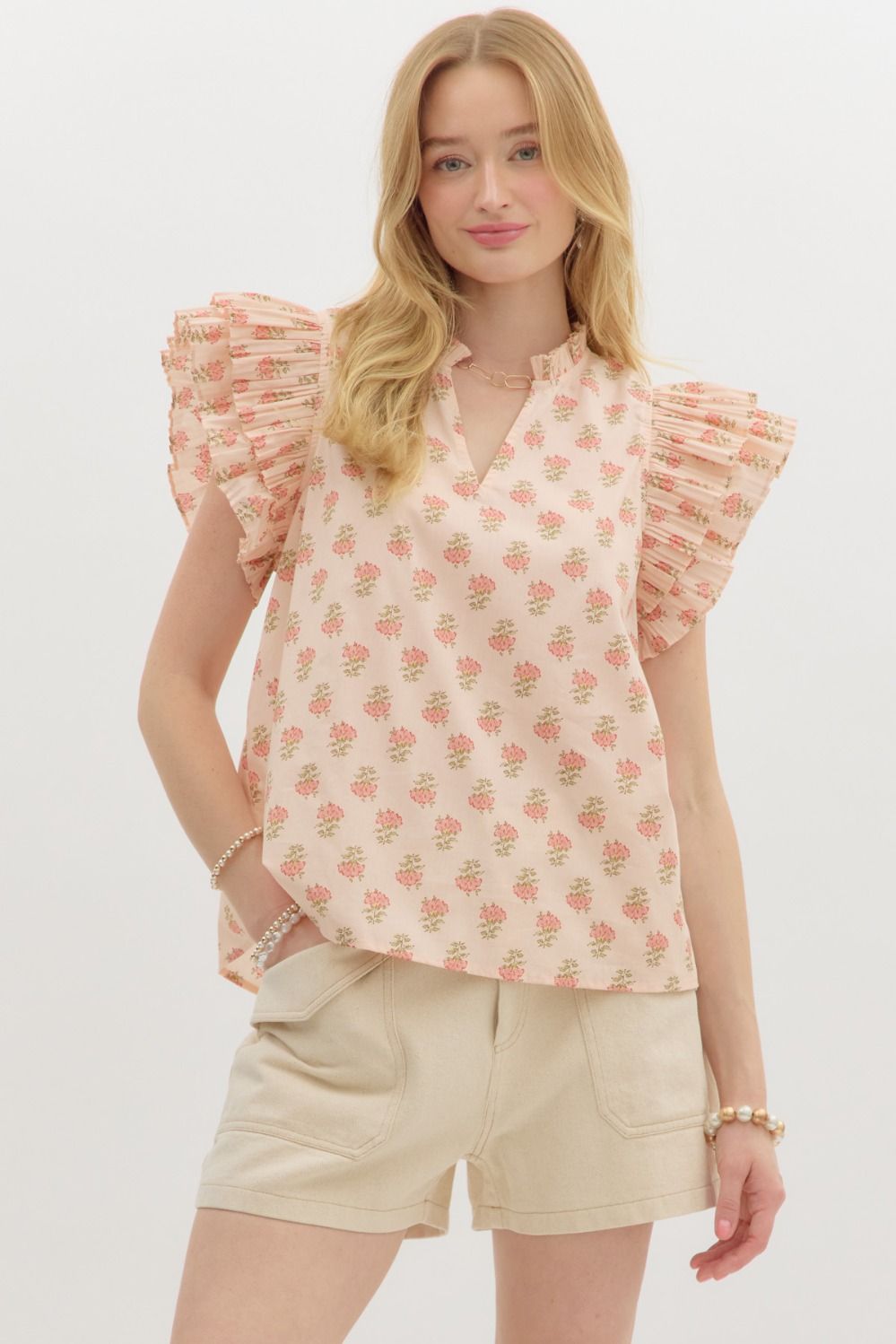 A flutter-sleeve floral top with pleated ruffles and tiered charm for a soft, feminine statement.