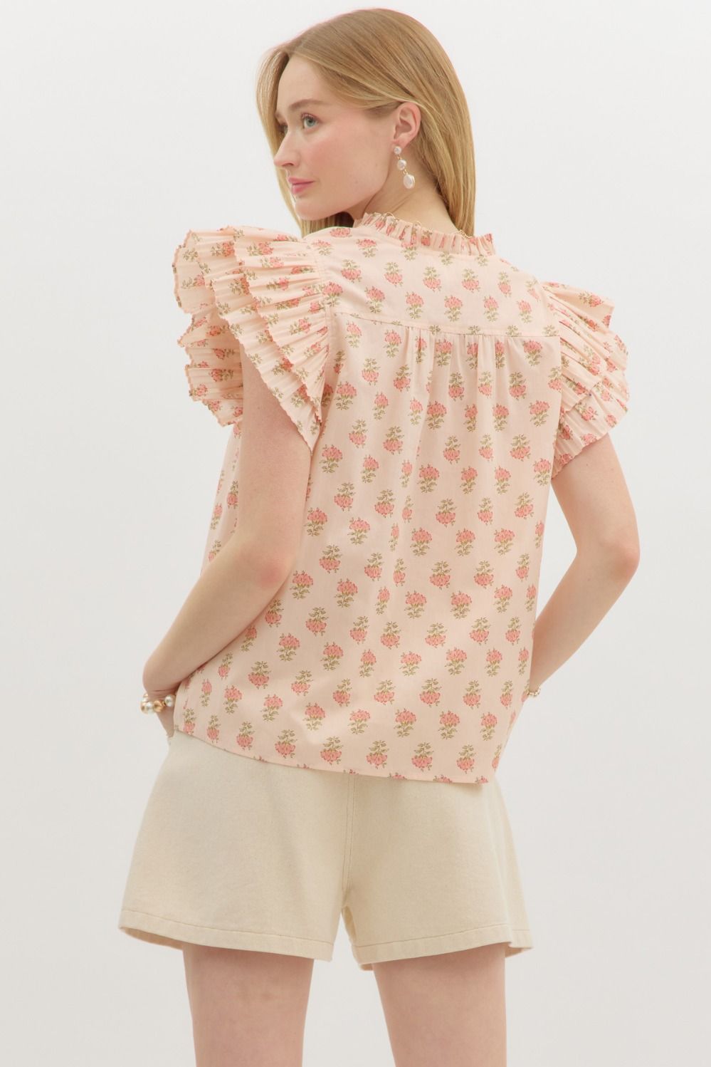 A flutter-sleeve floral top with pleated ruffles and tiered charm for a soft, feminine statement.