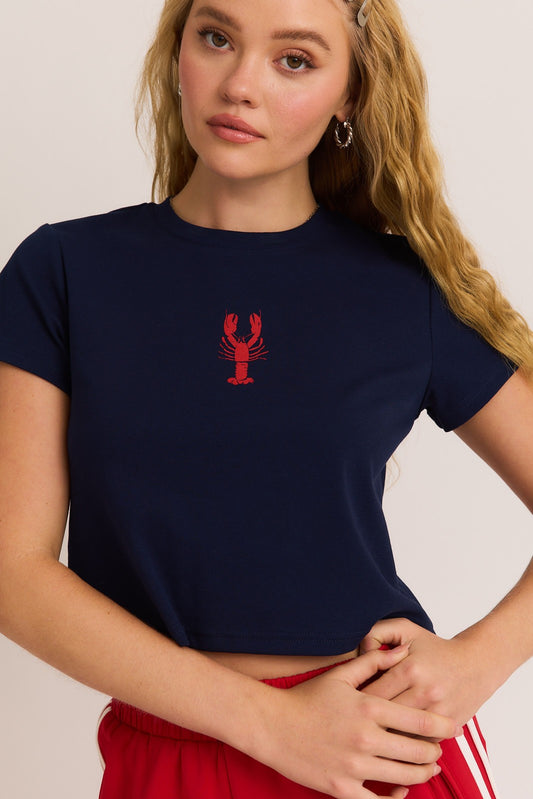 A fun and flirty baby tee featuring a bold lobster graphic and a classic round neckline—perfect for sunny days and casual vibes.