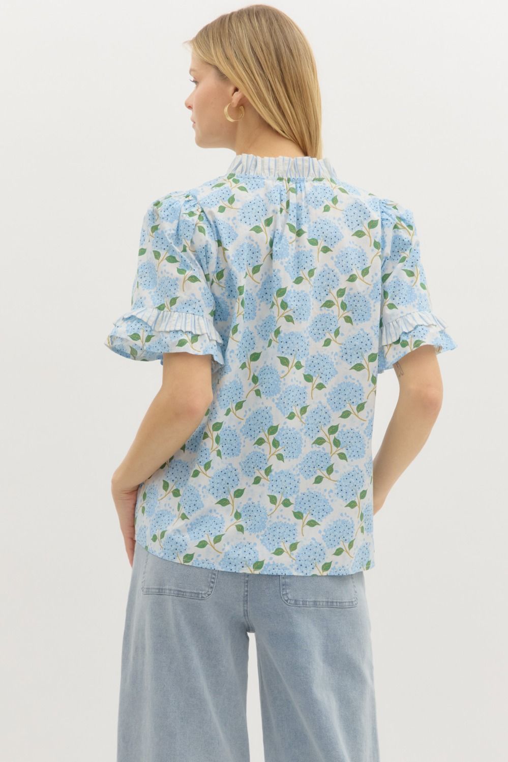A lightweight floral pullover top with playful contrast ruffle accents and a keyhole neckline.
