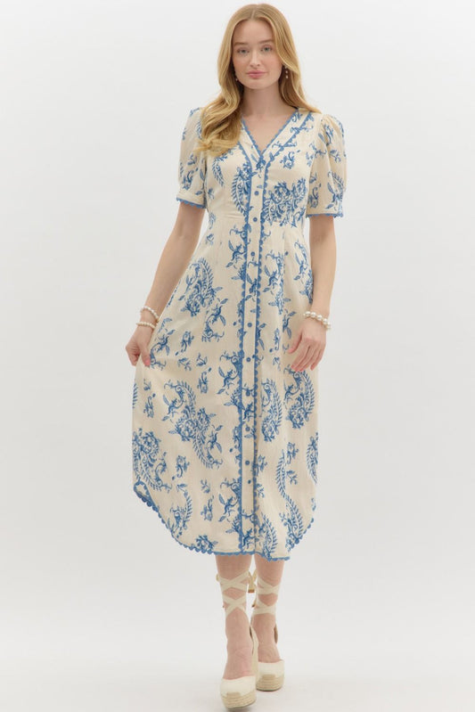 A pleated paisley midi dress with scalloped trim, self-tie waist, and graceful V-neckline.