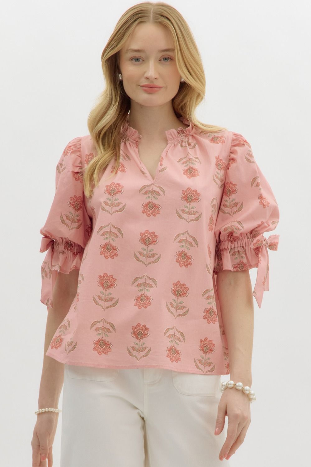 A romantic floral pullover top with a ruffled split neckline, bow accent, and bubble sleeves—feminine charm in an easygoing silhouette