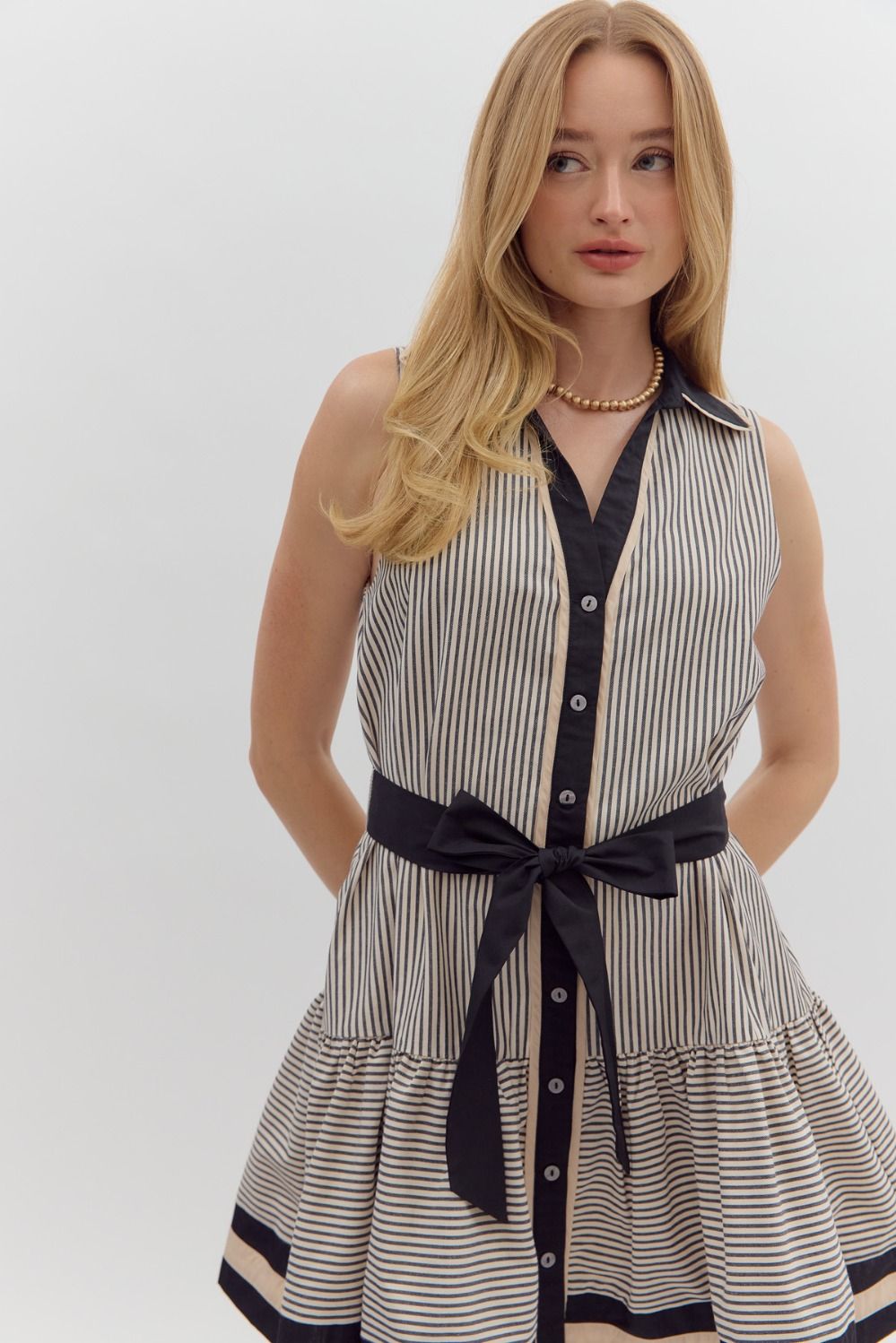 A striped sleeveless mini dress with ruffle hem, multicolor band detailing, and a removable belt.

