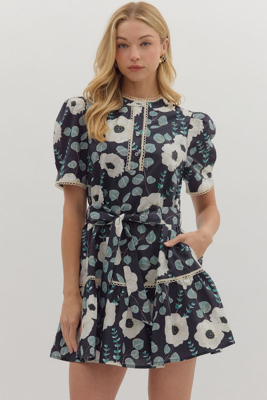A sweet floral mini dress with contrast trim, functional buttons, and a removable belt for versatile styling.

