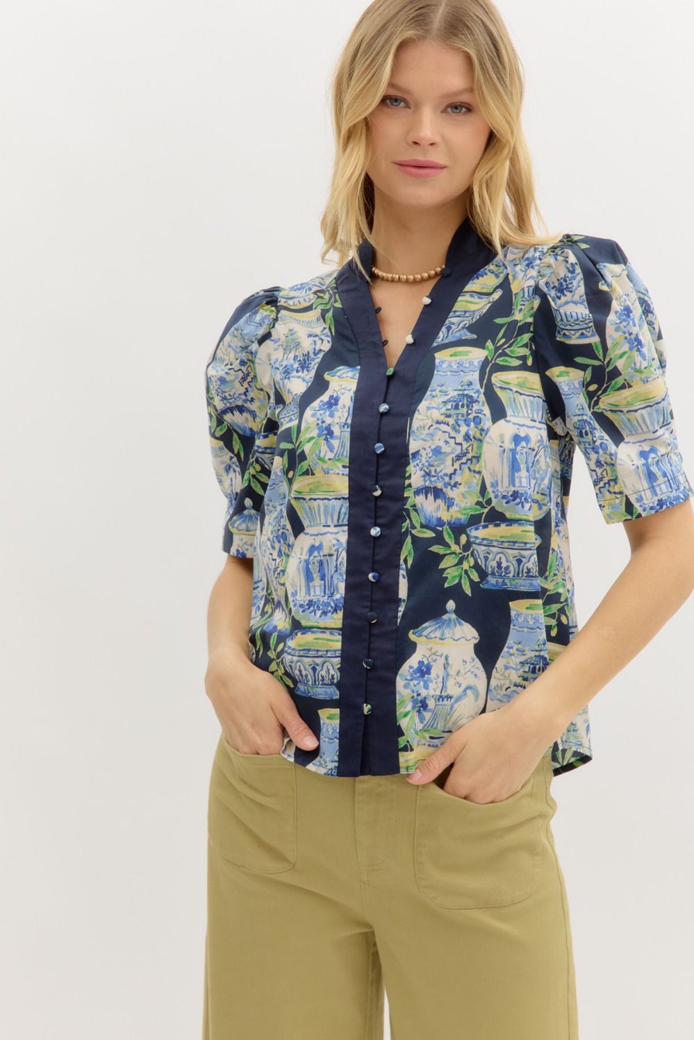 A whimsical garden landscape print top with puff sleeves and contrast placket detailing.