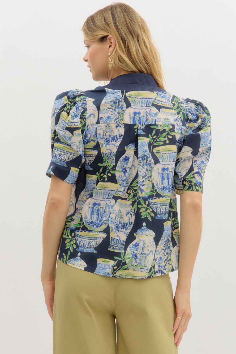 A whimsical garden landscape print top with puff sleeves and contrast placket detailing.

