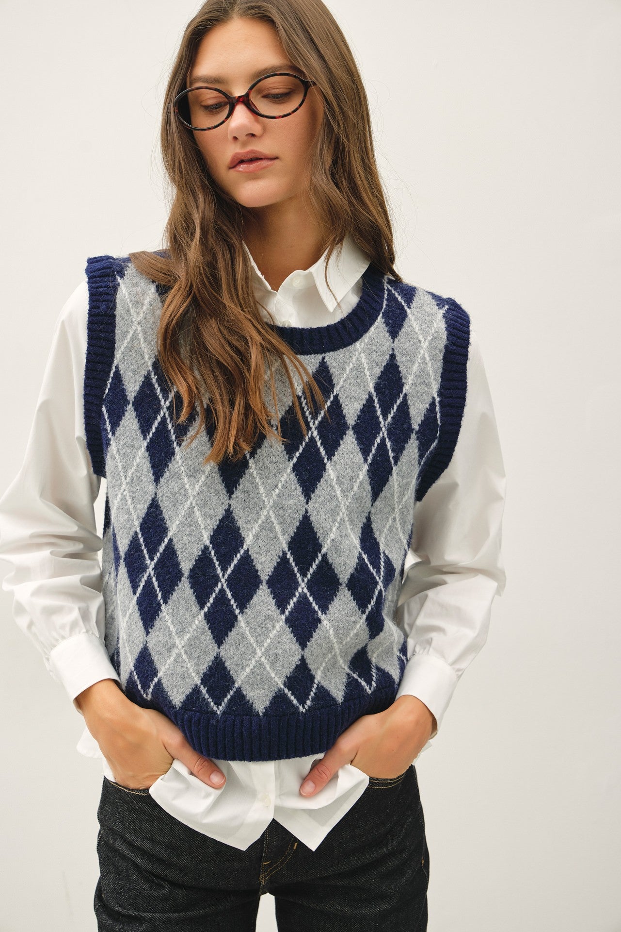 a navy and gray argyle knit sweater vest over a white collared shirt that is attached to the vest 