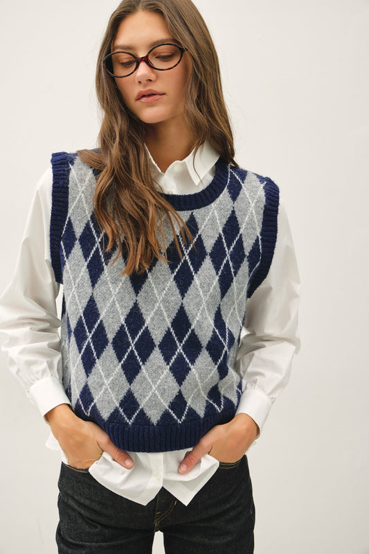 a navy and gray argyle knit sweater vest over a white collared shirt that is attached to the vest 