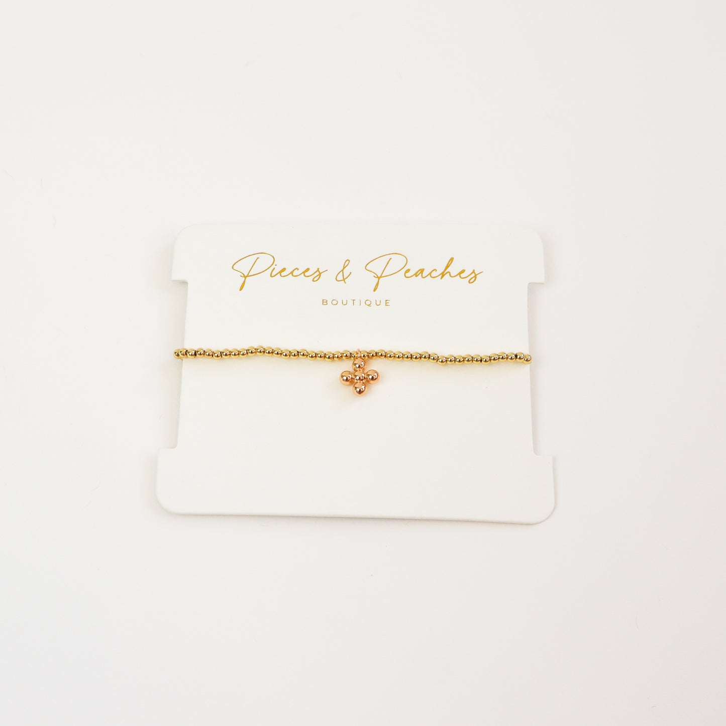 A minimal 4K gold-plated beaded bracelet adorned with a tiny ball bead cross charm for a dreamy, everyday look.
