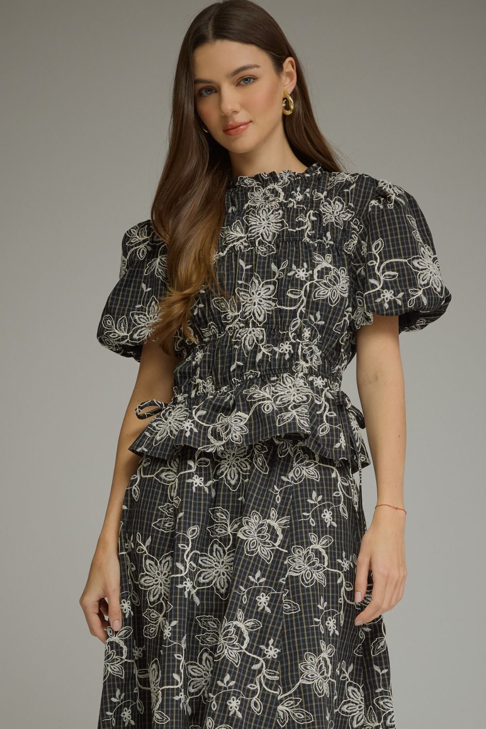A beautifully embroidered plaid top with puff sleeves and feminine ruffle details for an effortlessly charming look.